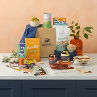 Assorted food products including candles, snacks, and beverages on a table with a neutral background.
