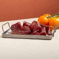 cecina, air dried beef, slices in a tray and tomatoes