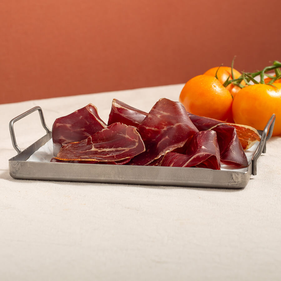 cecina, air dried beef, slices in a tray and tomatoes