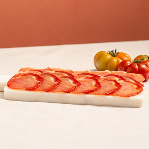 lomo (cured loin) slices in a tray and tomatoes