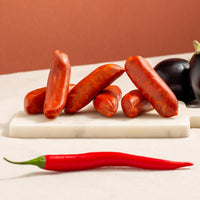 chorizo sausages on a marble board, vibrant red, a long chilly and two aubergines