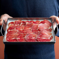100% Iberico lomo doblado (loin) slices in a tray hold by a man