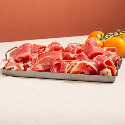 large portion of serrano ham slices in a tray and tomatoes