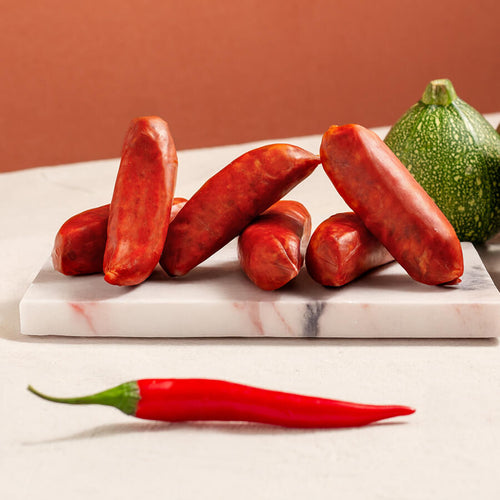 chorizo sausages on a marble board, a chilly pepper and moon courgettes