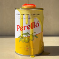 Perelló Olive oil tin with lots of olive oil drizzled on top of it