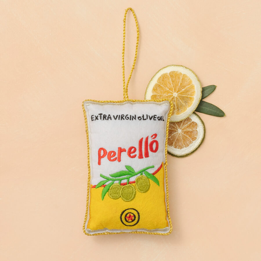 Decorative olive oil pouch with 'Perello' branding on a beige background with lemon slices.