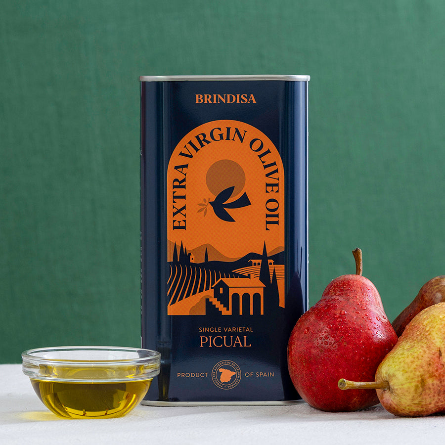 Brindisa extra virgin olive oil can with a bowl of olive oil and pears on a green background