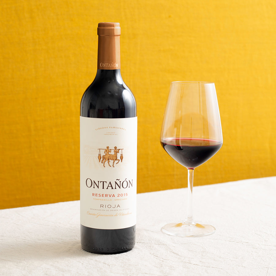 A bottle of red wine and a glass