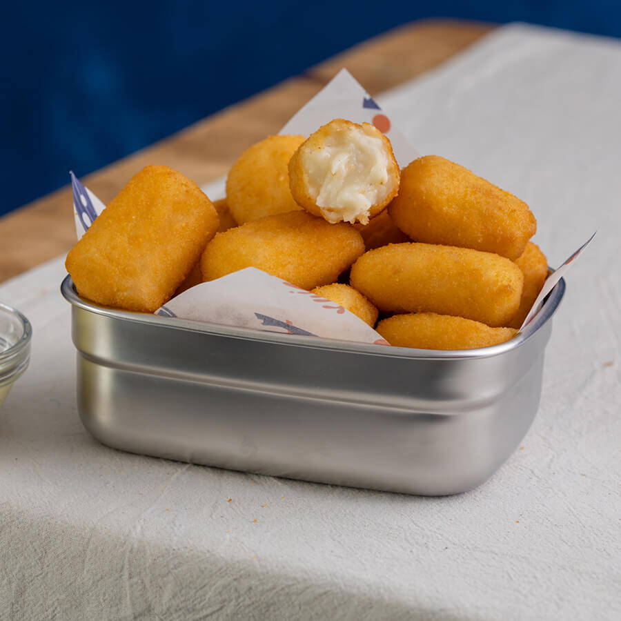Metal container filled with golden brown fried cod croquetas
