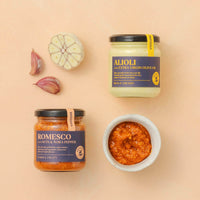 a jar of Romesco and a jar of Alioli sauce on a beige background