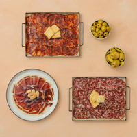 Plated charcuterie dishes with olives on a beige background