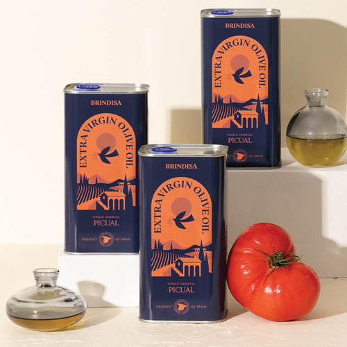Brindisa olive oil tins with a tomato on a light background