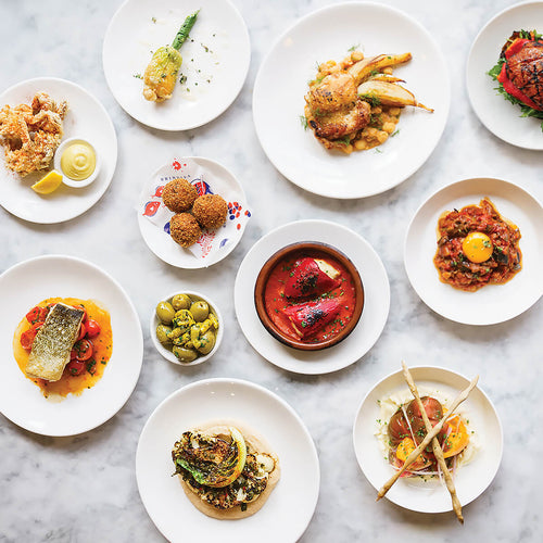 Assorted dishes on white plates arranged on a marble surface