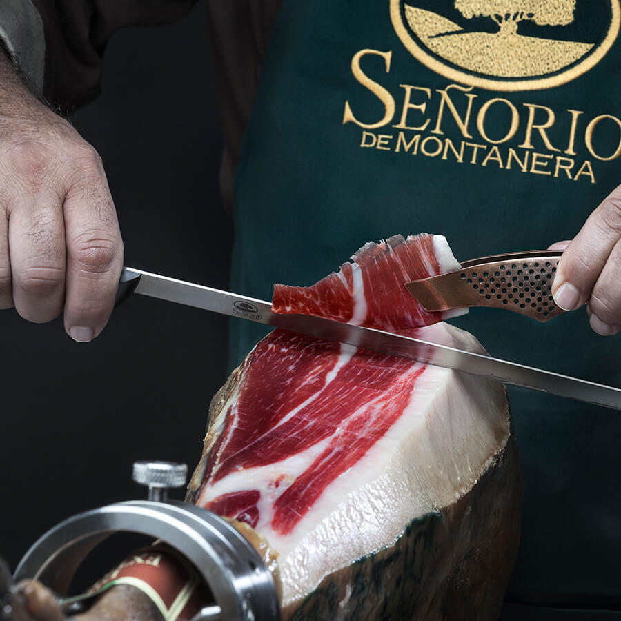 Person cutting a block of cured meat with a knife