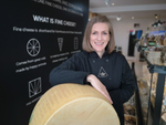 Svetlana The Cheese Lady standing next to a big parmesan wheel