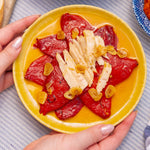 Yellow plate with piquillo peppers, ventresca and garlic held by a person.