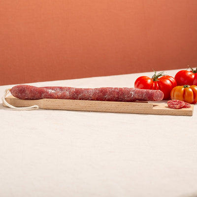 cured fuet sausage in a chopping board with two slices and three tomatoes