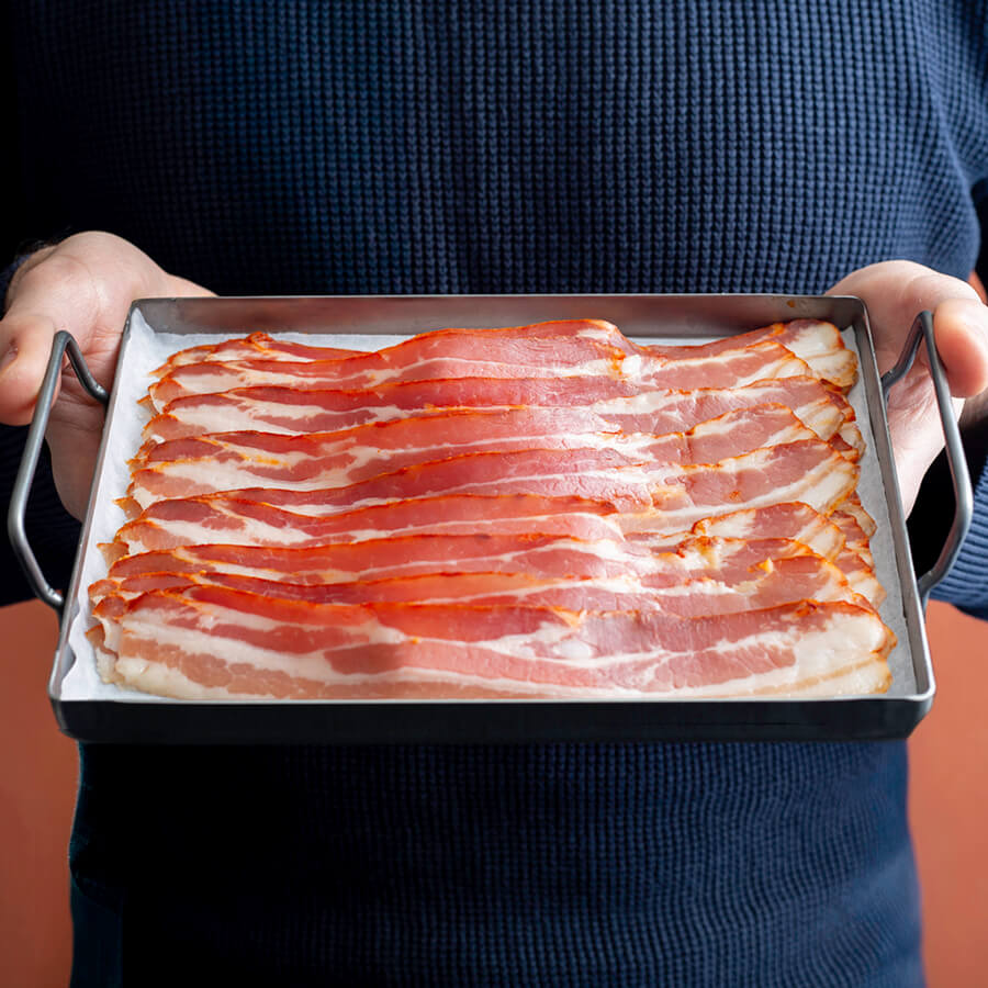 panceta bacon slices in a tray hold by a man