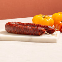 cured chorizo hoop in a marble chopping board with three yellow tomatoes