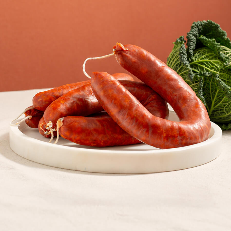 fresh chorizo hoop with a string in a marble tray and a savoy cabbage 