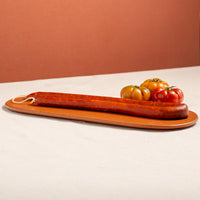 vasc country style chorizo, chistorra on a terracota tray. Thin and long with three tomatoes 