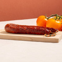 cured chorizo hoop in a chopping board and three yellow tomatoes