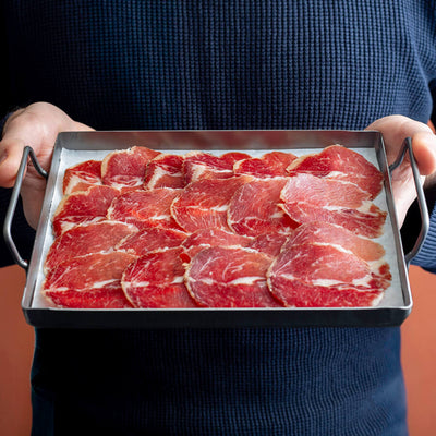 100% Iberico lomo doblado (loin) slices in a tray hold by a man