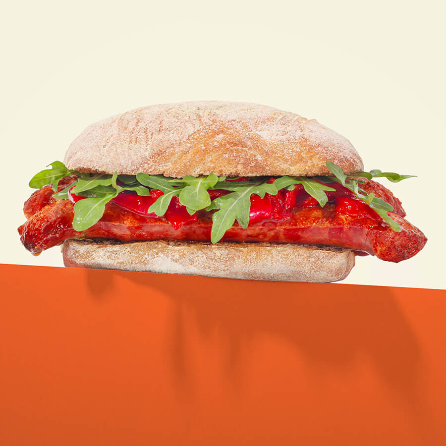 Sandwich with piquillo pepper and arugula on a plain background