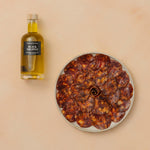 Dried cured meat on a plate with a bottle of truffle oil on a beige background