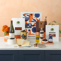 The holiday indulgence hamper, including gourmet food and wine, set on a table with a decorative background