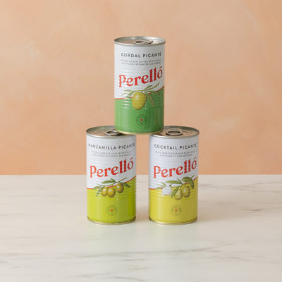 Three tins of Perello on a white surface with a peach-colored background