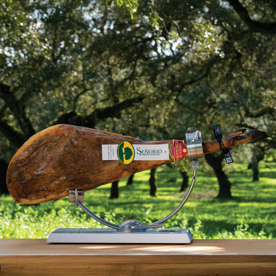 Senorio 100% iberico ham on th bone on a wooden board with a label in an outdoor setting