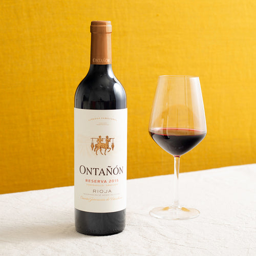 A bottle of red wine and a glass