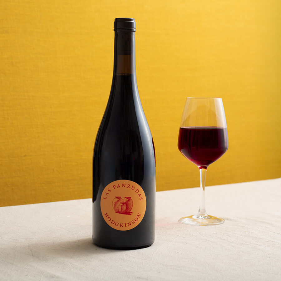 a bottle of red wine with a glass of the same wine, dark red