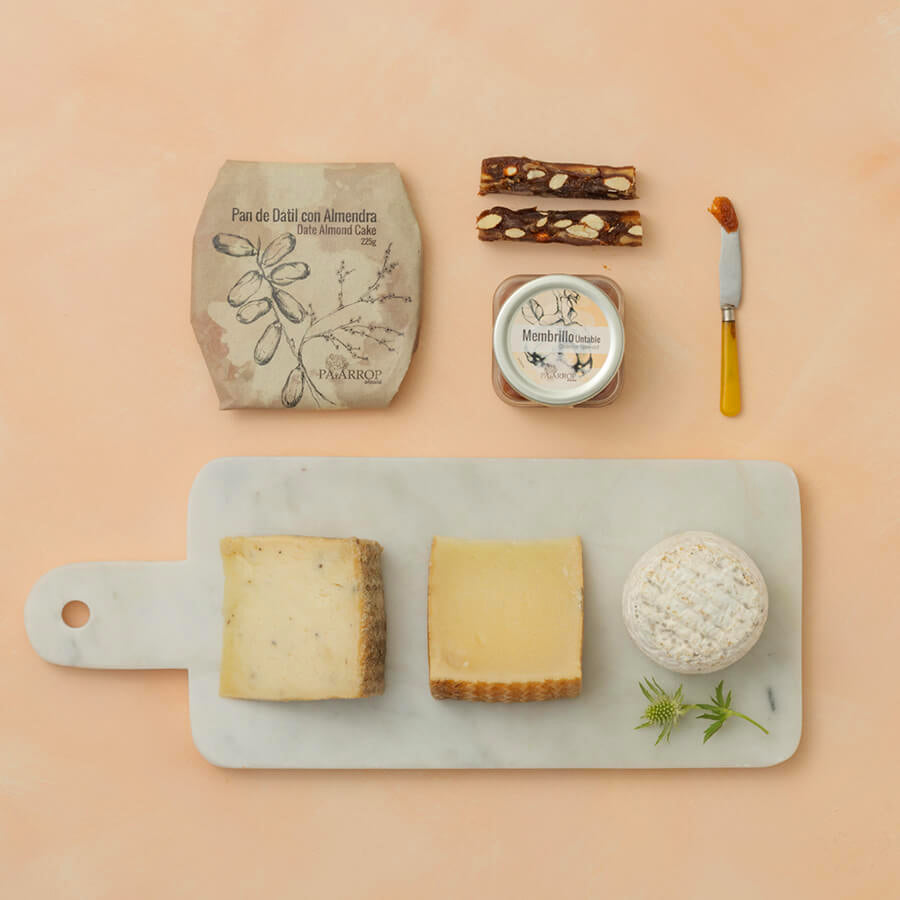 Assorted cheeses on a marble board with quince, dried food and knife on a beige background
