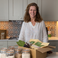 Monika in the kitchen with her pulse subscription box and some jars with dried beans next to it 